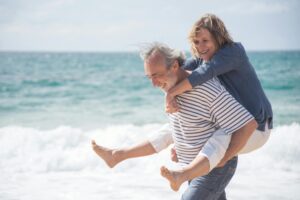 Happy senior couple on a beach in Portugal, sharing a joyful moment by the ocean.