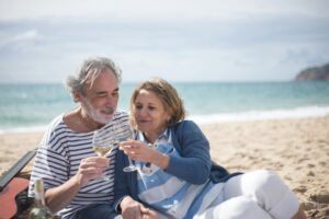Happy senior couple enjoying a romantic moment with wine on a scenic beach in Portugal.