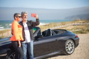 Elderly couple enjoys a scenic seaside drive in Portugal, capturing memories with a selfie.